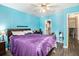 This bedroom includes a hardwood floor, bright blue walls, a ceiling fan with a lighting, and bedroom furniture at 989 Queen Elizabeth Way, Morrow, GA 30260