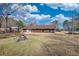 Backyard view of the home, surrounded by grass and a few trees under a bright blue sky at 11 Grove Ln, Hampton, GA 30228