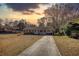 Cozy single-story brick home with a charming front porch and a long driveway under a captivating sunset sky at 11 Grove Ln, Hampton, GA 30228