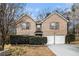 Two-story brick home featuring two garage doors, manicured shrubs, and a well-maintained lawn at 5803 Star Flower Dr, Ellenwood, GA 30294