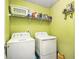 Functional laundry room with washer, dryer, shelving, and wall hooks for storage at 5803 Star Flower Dr, Ellenwood, GA 30294