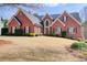 Beautiful brick home with well-manicured lawn and mature trees on a sunny day at 1300 Village Oaks Ln, Lawrenceville, GA 30043