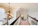 Elegant hallway on the second story with a chandelier, a staircase, and neutral colors at 1300 Village Oaks Ln, Lawrenceville, GA 30043