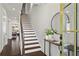 Inviting entryway with hardwood floors, staircase, and a stylish console table with plants and mirror at 13 Ganel Ln, Alpharetta, GA 30009