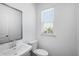 Bright half bathroom with a white vanity, toilet, and a window offering natural light at 1745 Lansmere Sw St, Marietta, GA 30008