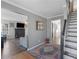 Hallway with grey walls leading to the living room with a fireplace, and staircase with a dark wood handrail at 526 Lakeside Dr, Hiram, GA 30141