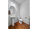 Bathroom with modern pedestal sink, toilet, and hardwood floors offers a clean and stylish look at 6801 Louis Dr, Locust Grove, GA 30248