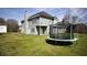 Green backyard with the home's back elevation and a trampoline for Gathering enjoyment at 70 Woodcliff Way, Covington, GA 30014