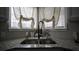 Kitchen sink with granite countertop and black faucet is accented by the white cafe curtains and decor at 70 Woodcliff Way, Covington, GA 30014