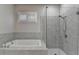 Modern bathroom showcasing a tiled shower with glass door and a separate soaking tub under a window at 1043 Harvest Park Ln, Suwanee, GA 30024