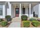 Inviting front porch with brick steps, white columns, and stylish hanging lanterns at 1043 Harvest Park Ln, Suwanee, GA 30024