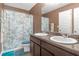 Well-lit bathroom with double sinks, granite countertops, and a shower/tub with a blue leaf-patterned shower curtain at 1152 Werre Way, Locust Grove, GA 30248