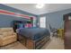 Comfortable bedroom with blue accent wall, an area rug, a desk, and a bed with built-in storage at 1152 Werre Way, Locust Grove, GA 30248