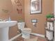 Cozy powder room featuring a pedestal sink, decorative butterfly accents, and earth-toned decor at 1152 Werre Way, Locust Grove, GA 30248