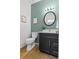 This powder room features a modern vanity, round mirror, and light green wall at 3595 Evonvale Overlook, Cumming, GA 30041