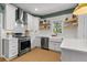 Bright kitchen features white cabinetry, stainless appliances, herringbone backsplash, and open shelving at 3595 Evonvale Overlook, Cumming, GA 30041