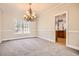 Light and airy carpeted dining room shows a chandelier and view of the kitchen through an open doorway at 100 Hamilton Glen Ct, Fayetteville, GA 30215