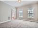 The carpeted living room is spacious and well lit with 2 windows and a view of the front entry at 100 Hamilton Glen Ct, Fayetteville, GA 30215