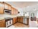 Bright kitchen featuring wood cabinets, granite countertops, and stainless steel appliances next to a casual living area at 1111 Newpark View Pl, Mableton, GA 30126