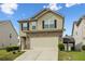 Two-story home featuring tan siding, brick accents, an attached garage, and a well-manicured lawn at 6119 Hickory Lane Dr, Union City, GA 30291