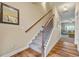 Hallway with hardwood floors, carpeted stairs, wood railings, and decorative artwork at 6119 Hickory Lane Dr, Union City, GA 30291