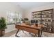 Well-lit office with a large desk, shelving unit, and natural light from the window at 4273 Creekrun Cir, Buford, GA 30519