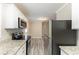 Open kitchen with granite countertops, stainless steel appliances, and gray wood floors at 6202 Humphries Hill Rd, Austell, GA 30106