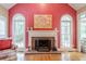 Bright living room featuring a red accent wall, fireplace, hardwood floors, and large arched windows at 6360 Brookline Ct, Cumming, GA 30040