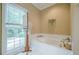 Relaxing main bathroom featuring a soaking tub, large window, and neutral decor at 6360 Brookline Ct, Cumming, GA 30040