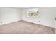 Empty bedroom featuring neutral carpet, white walls, natural light, and a window with a view of the neighborhood at 7025 Kimberly Mill Rd, Atlanta, GA 30349