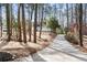 Long concrete driveway leading to a modern home surrounded by tall trees at 2626 Shadow Woods Ne Cir, Marietta, GA 30062