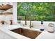 Close-up on sink with backyard view and gold colored faucet fixtures, with white countertops at 3882 The Ascent Ne, Brookhaven, GA 30319