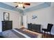 Spacious bedroom featuring a tray ceiling, ceiling fan, dark wood furniture, and neutral walls at 1670 Hampton Walk Dr, Hoschton, GA 30548