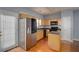 Kitchen featuring stainless steel refrigerator, black appliances, and wood cabinets on hardwood floors at 5381 Briar Creek Ln, Norcross, GA 30071