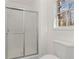 White bathroom featuring a large window and a glass-door shower at 305 Bridgewater Ter, Canton, GA 30115