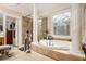 A bright bathroom features a soaking tub under a decorative window, flanked by white pillars and tile work at 4040 Annecy Dr, Atlanta, GA 30331