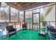 Screened porch with outdoor seating and green carpet overlooks the backyard at 4558 Bronte Ln, Douglasville, GA 30135