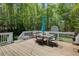 Outdoor dining area on a wooden deck, surrounded by a lush forest backdrop at 6935 Autumn Hills Dr, Cumming, GA 30028