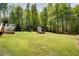 Lush backyard showcases a shed and greenhouse, perfect for gardening enthusiasts at 6935 Autumn Hills Dr, Cumming, GA 30028