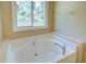 Bright bathroom featuring a white oval bathtub and a large window overlooking the backyard at 6935 Autumn Hills Dr, Cumming, GA 30028