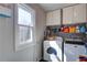 Bright laundry room features a washer, dryer, storage cabinets and a large window at 6935 Autumn Hills Dr, Cumming, GA 30028