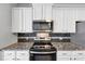 Modern kitchen featuring granite countertops, a mosaic backsplash and white cabinets at 7104 Skippingstone Way, Douglasville, GA 30134