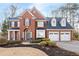 Charming brick two-story home boasts a three-car garage and meticulously landscaped front yard at 1026 Wellesley Crest Dr, Woodstock, GA 30189