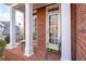 Inviting front porch with brick flooring and white columns, furnished with wrought-iron chairs at 1026 Wellesley Crest Dr, Woodstock, GA 30189