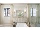 Bright bathroom with white cabinetry, sconces, soaker tub and view of the outside at 4555 Mystic Dr, Atlanta, GA 30342