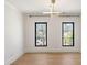Bright bedroom with light hardwood floors, modern light fixture, and black frame windows overlooking nature at 4555 Mystic Dr, Atlanta, GA 30342