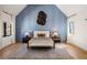 Well lit bedroom with a light blue accent wall, a cream colored bed and dark wood floors at 4555 Mystic Dr, Atlanta, GA 30342