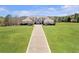 Beautiful front elevation on a large lot with long brick driveway and lush lawn with mature shrubbery at 525 Waters Way, Fayetteville, GA 30215