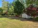 Expansive backyard with lush green lawn, surrounded by mature trees, sitting area, and storage shed at 4038 Se Clay Court Se Se, Conyers, GA 30013
