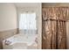 Bright bathroom featuring a bathtub with a sheer curtained window and a stylish shower curtain at 5884 Grande River Rd, Atlanta, GA 30349